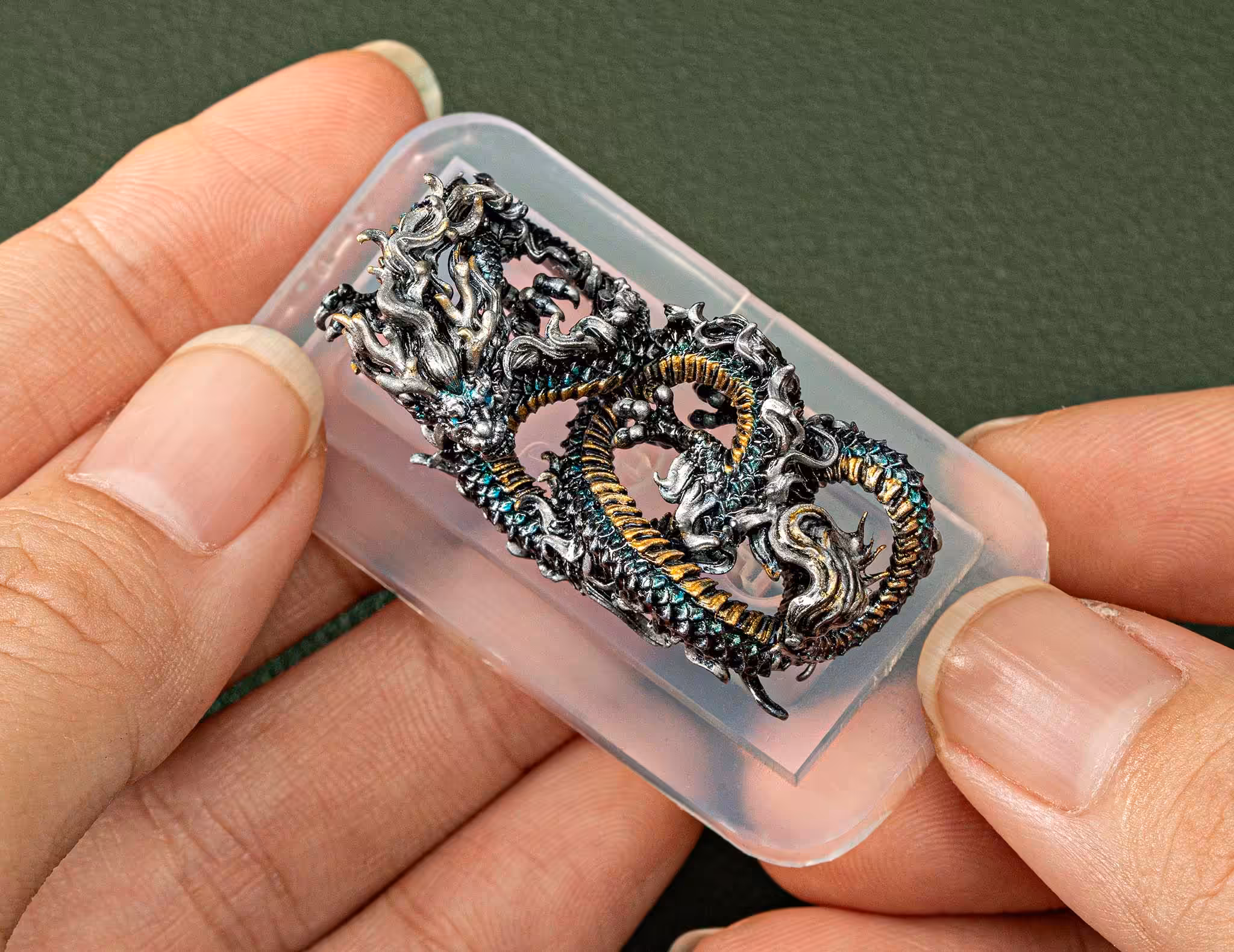 Hand holding intricate dragon sculpture keycaps in resin.