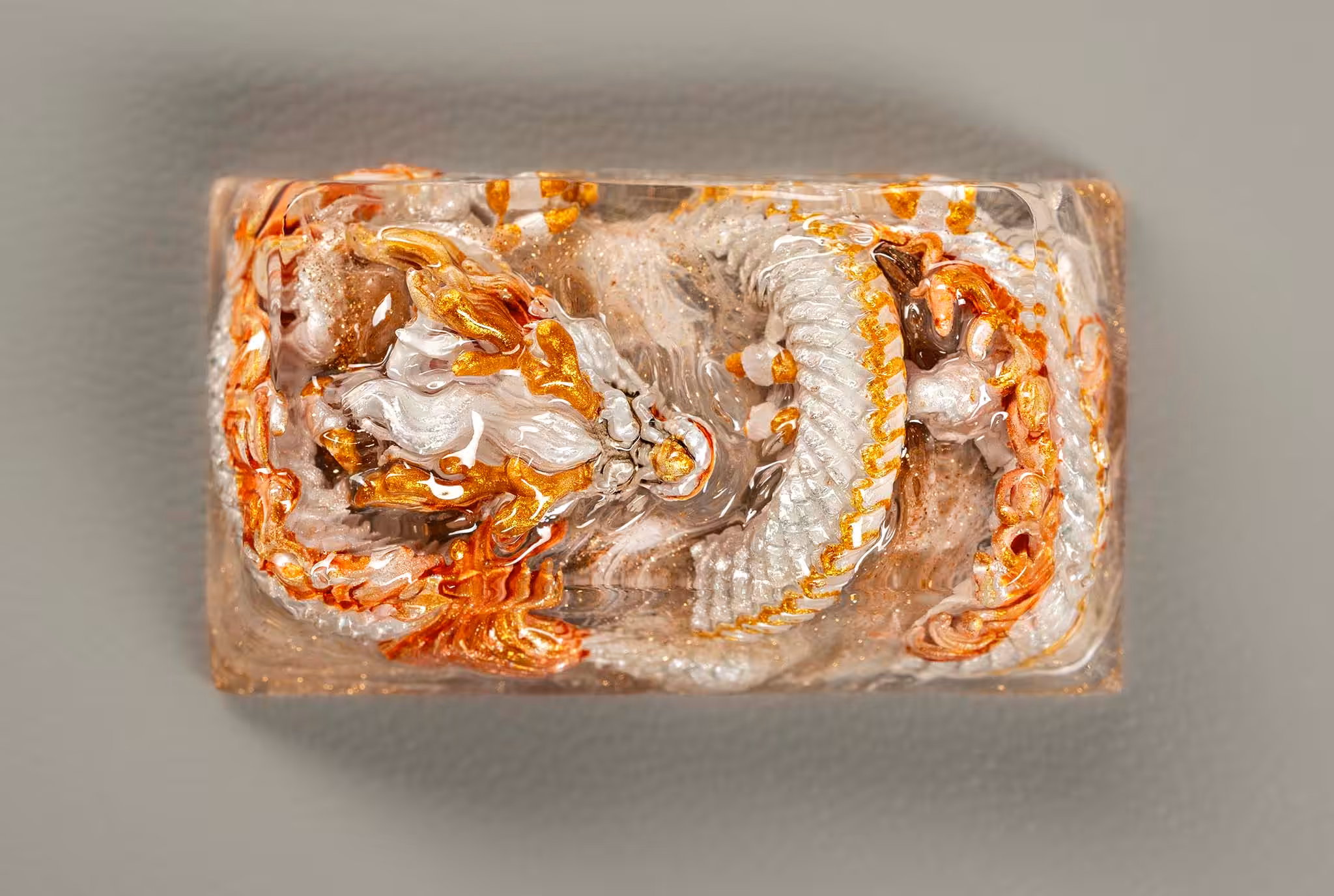 Decorative glass paperweight with gold and silver dragons.